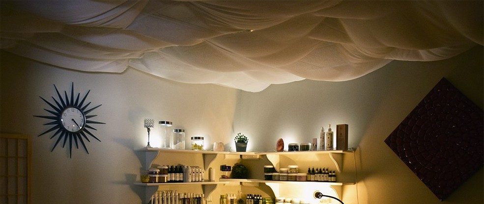 Treatment room with draped ceiling and backlit shelving at Wellness Origin Spa